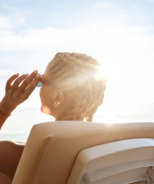 Beautiful girls in swimwear sunbathing, lying on chaises near sea. Young beautiful girls in swimwear sunbathing, lying on chaises near sea. Copy space.